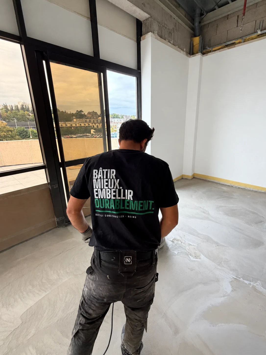 Compagnon BATILI de dos sur un chantier intérieur, portant le maillot Bâtir mieux. Embellir durablement.